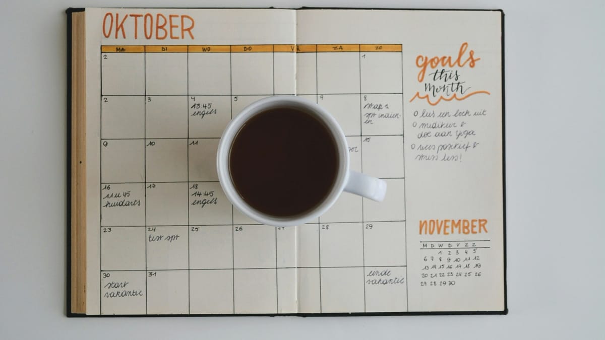 Cup of coffee sits on top of an open planner